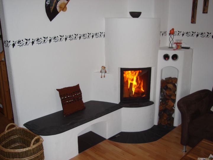 Heizkamin mit Ofenbank, Holznische und brennendem Feuer