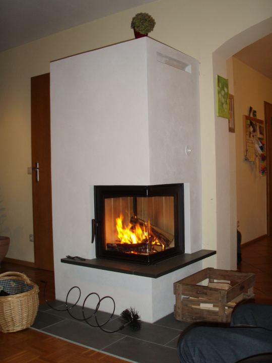 Hoher weißer Eck-Heizkamin mit Holzkorb
