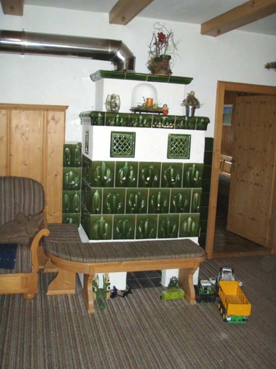 Grüner Kachelofen mit Ofenbank im Wohnzimmer