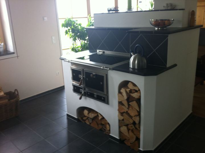 Holzherd mit dunkler Fliesenrückwand und zwei Holzfächern