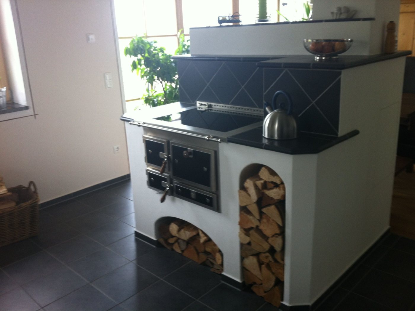 Holzherd mit dunkler Fliesenrückwand und Holzfächern