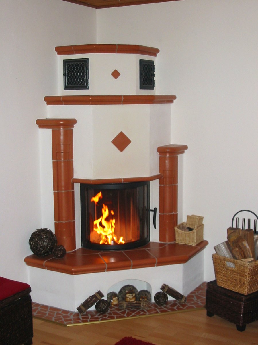 Eck-Heizkamin mit Terrakotta-Kacheln, Säulen und brennendem Feuer – gebaut von Ofenzauber